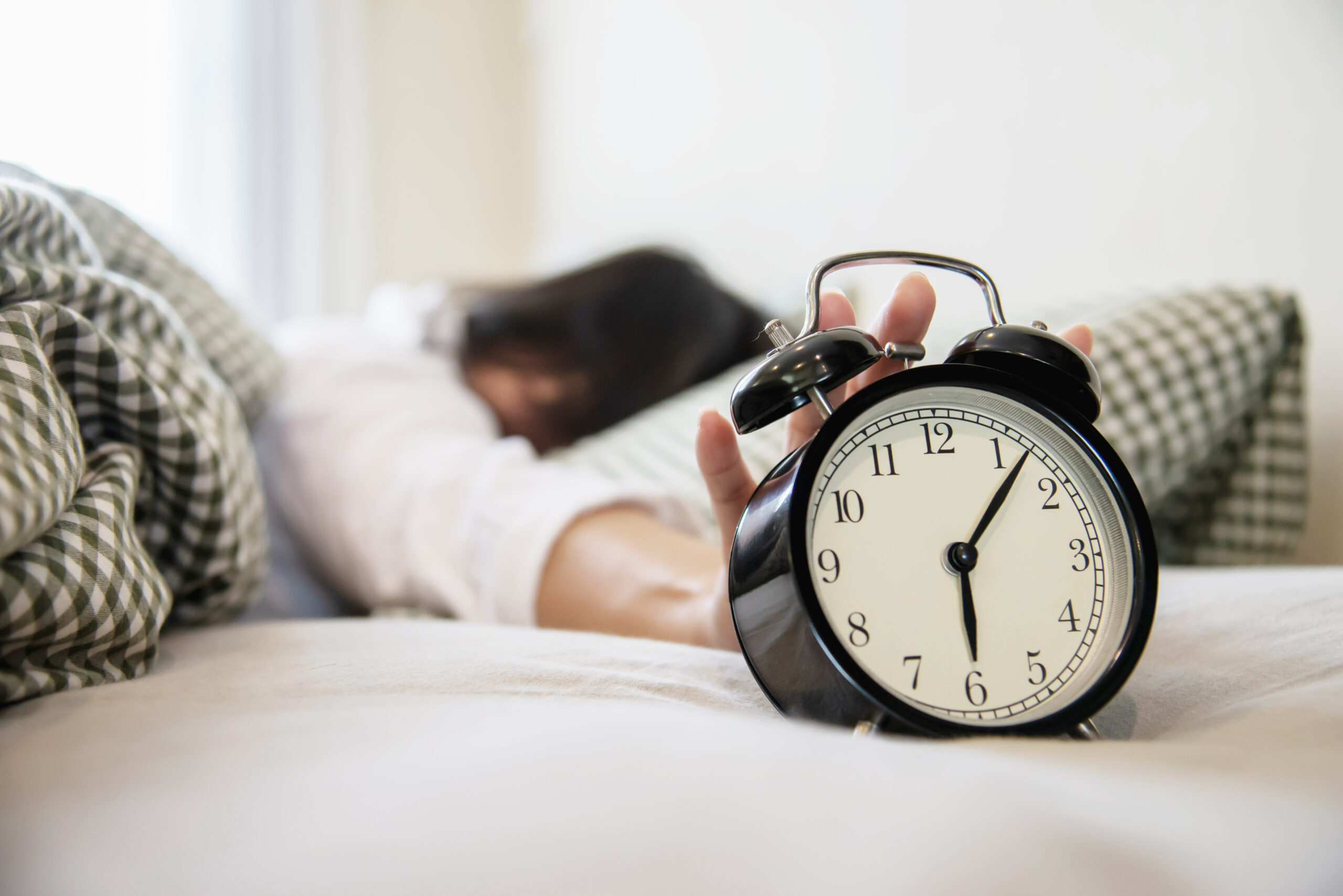 sleepy-woman-reaching-holding-alarm-clock-scaled-1